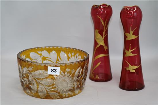 A pair of Philip Webb style parcel gilt cranberry glass vases, decorated with songbirds, and an amber glass bowl